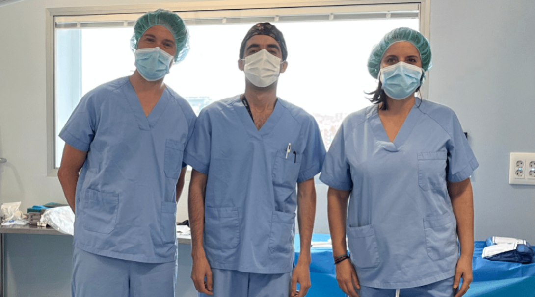 Two medical volunteer posing next to a surgeon during their medical internship